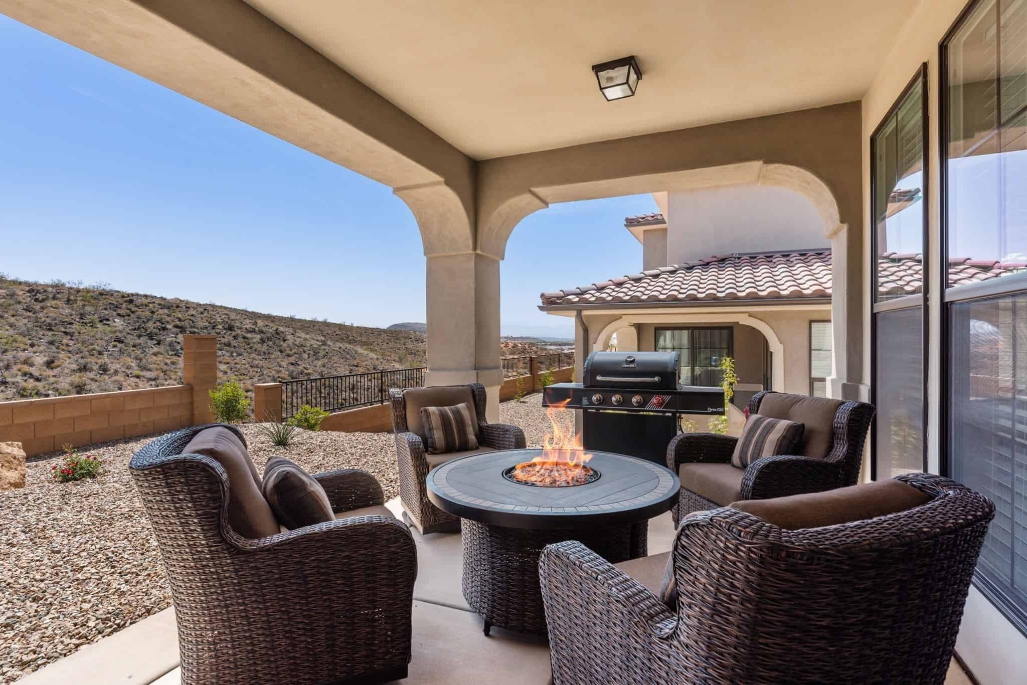A covered patio with wicker furniture, a fire pit, and a grill.