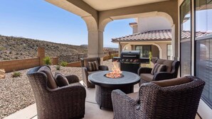 Un patio techado con mobiliario de mimbre, una chimenea y una parrilla.