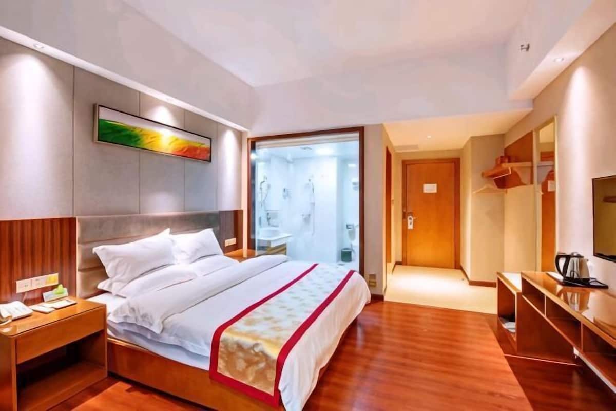 A hotel room with a bed, bedside table, and a TV.