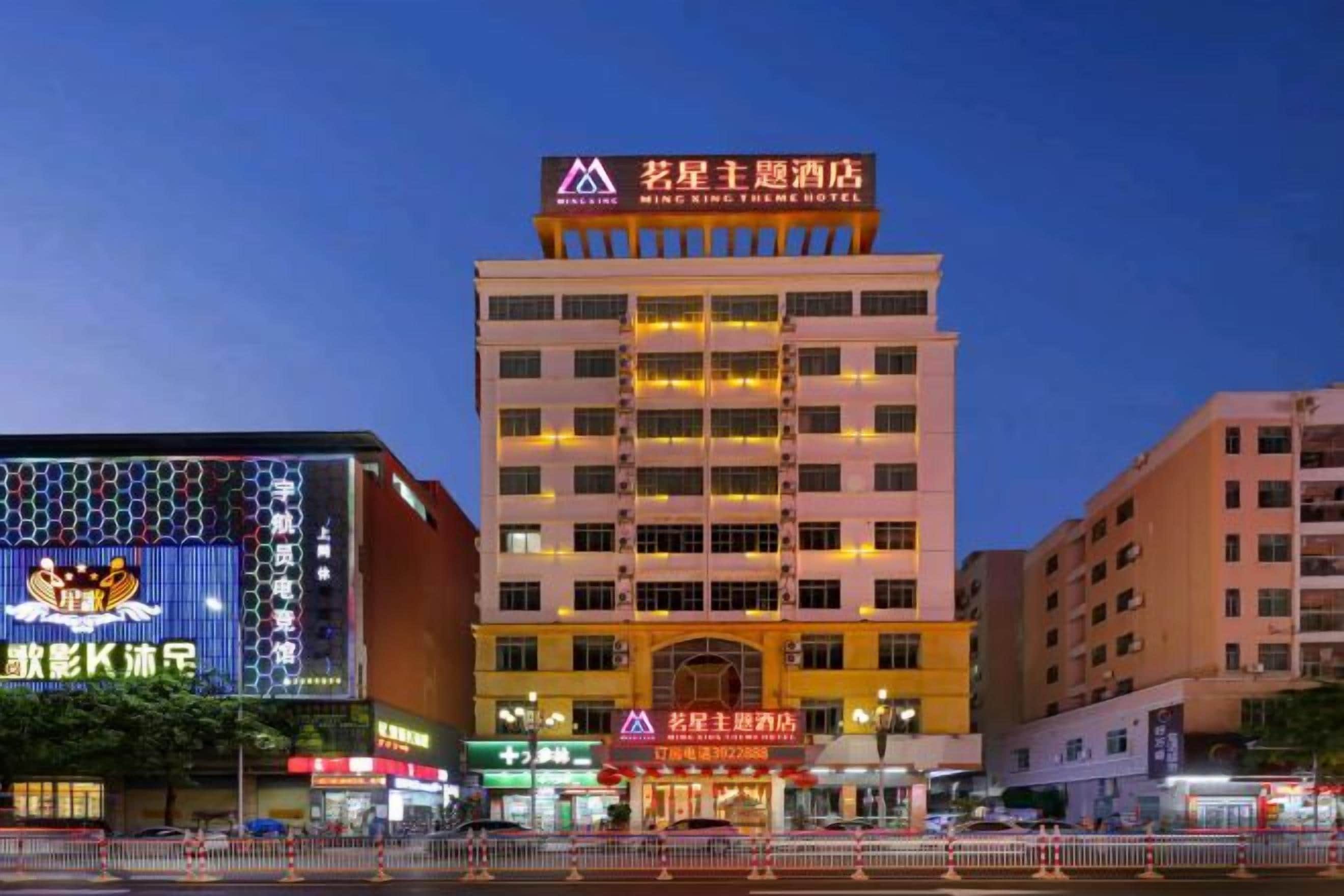 A multi-story hotel with a prominent sign at the top, multiple balconies, and a well-lit facade.