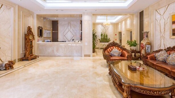 Um hall amplo com balcão de recepção, um conjunto de sofás, uma mesa de centro e um candelabro.