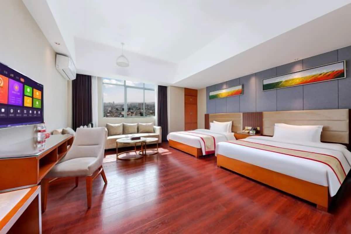 A hotel room with a large bed, a desk, a sofa, and a TV.