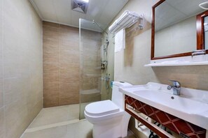 Un baño con ducha envuelta en vidrio, inodoro blanco y tocador con espejo.