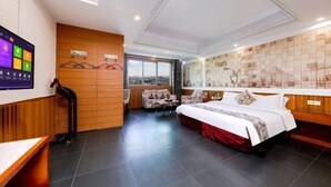 Quarto de hotel com cama, sofá, televisão e vista para a cidade.