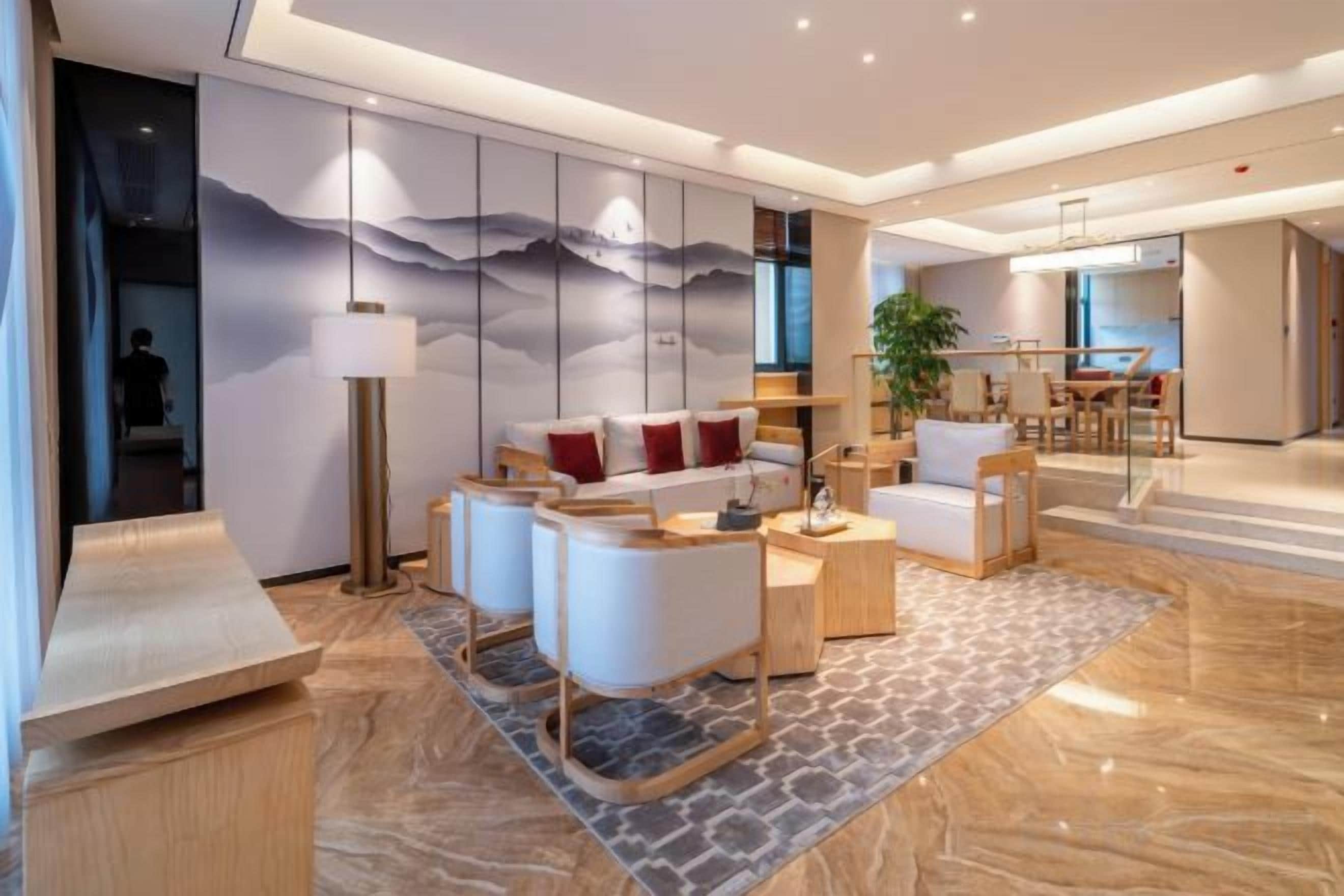 Una sala de estar moderna con un sofá, sillones, una mesa de centro y un tapete estampado.