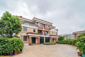 A multi-story residential building with a spacious courtyard, potted plants, and a clear sky. - Aile Holiday Hotel (Sanming)