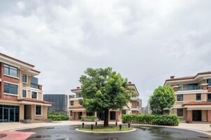 Un complejo residencial con varios edificios de apartamentos, una rotonda central y un gran árbol.
