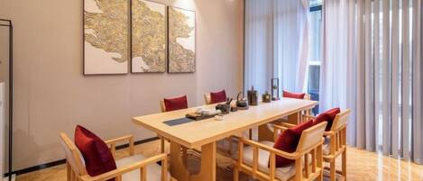A dining area with a long table and chairs, a chandelier, and artwork on the wall.