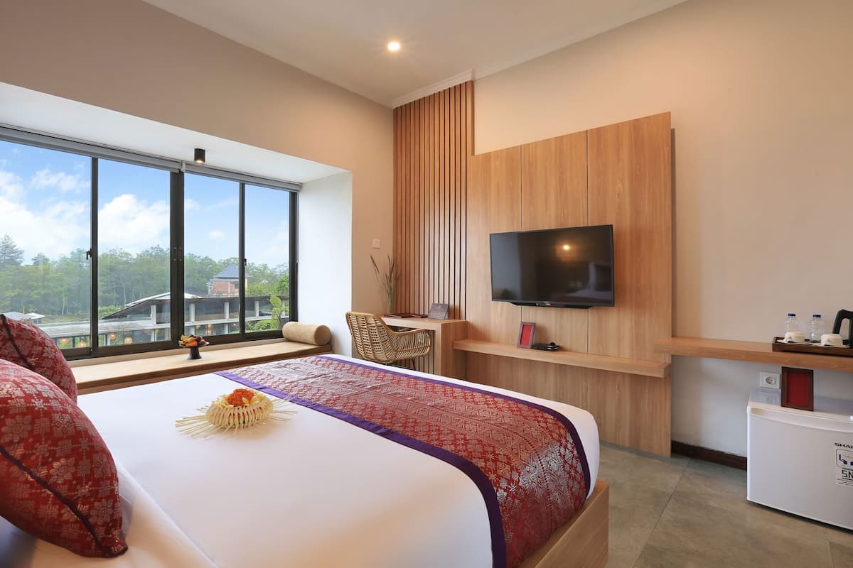 Une chambre d’hôtel avec un grand lit, un téléviseur fixé au mur, un bureau et une vue sur l’extérieur.