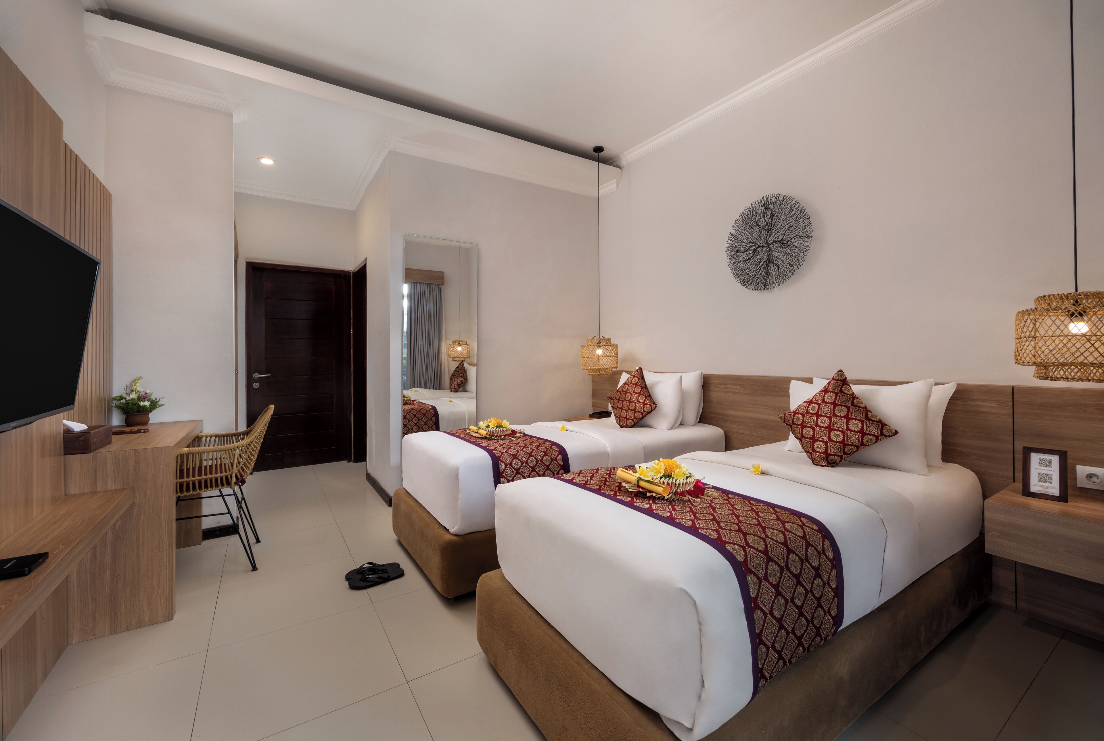 A hotel room with two beds, a desk, a TV, and a mirror.