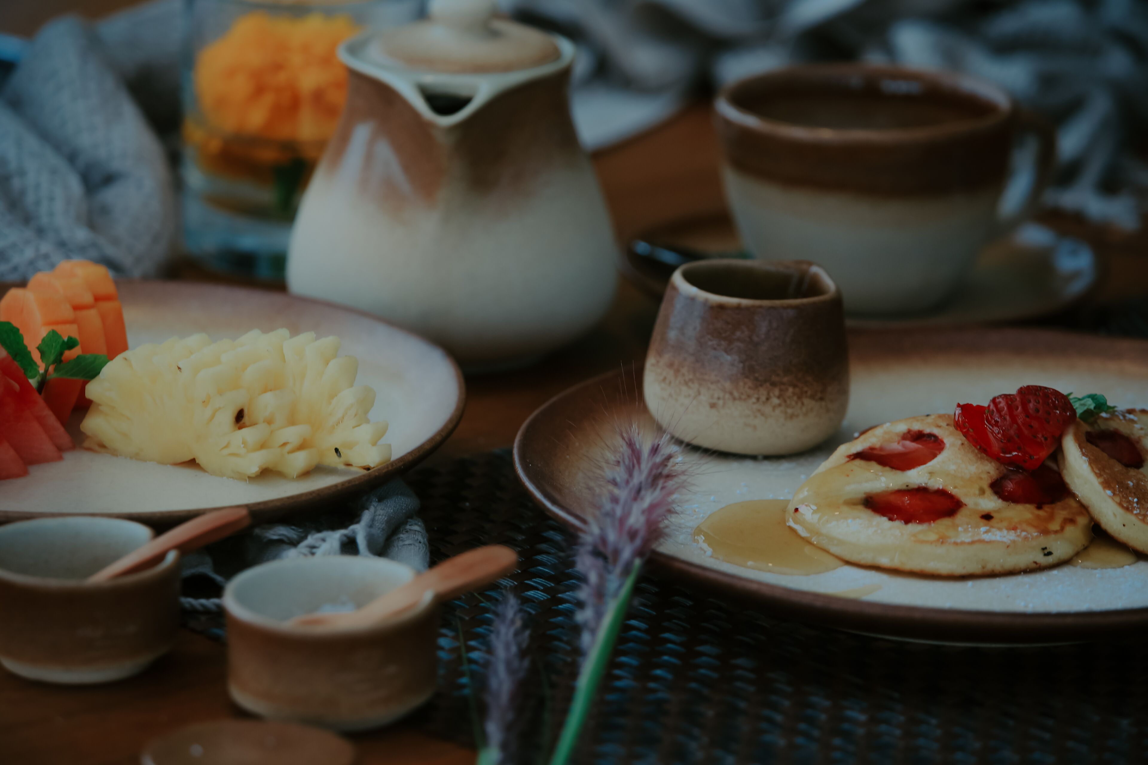 Une table dressée avec des assiettes remplies de nourriture, une théière et de petites tasses.