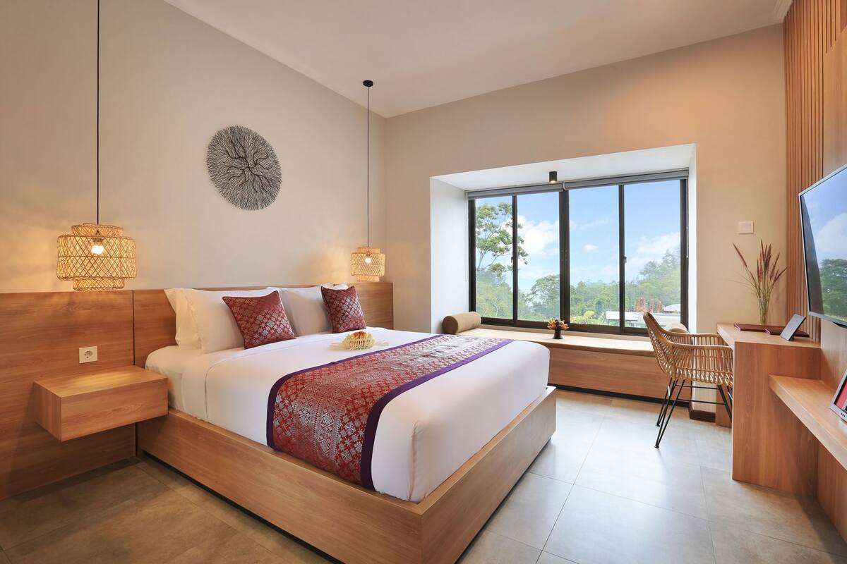 Une chambre moderne avec un grand lit, des tables de chevet, un bureau et un téléviseur.