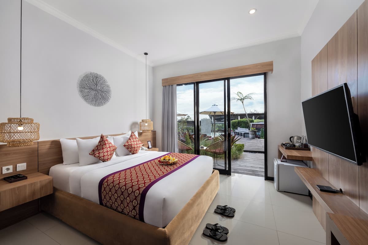 Een moderne hotelkamer met een groot bed, een flatscreen televisie, een houten bureau en een balkon met uitzicht op de omgeving.