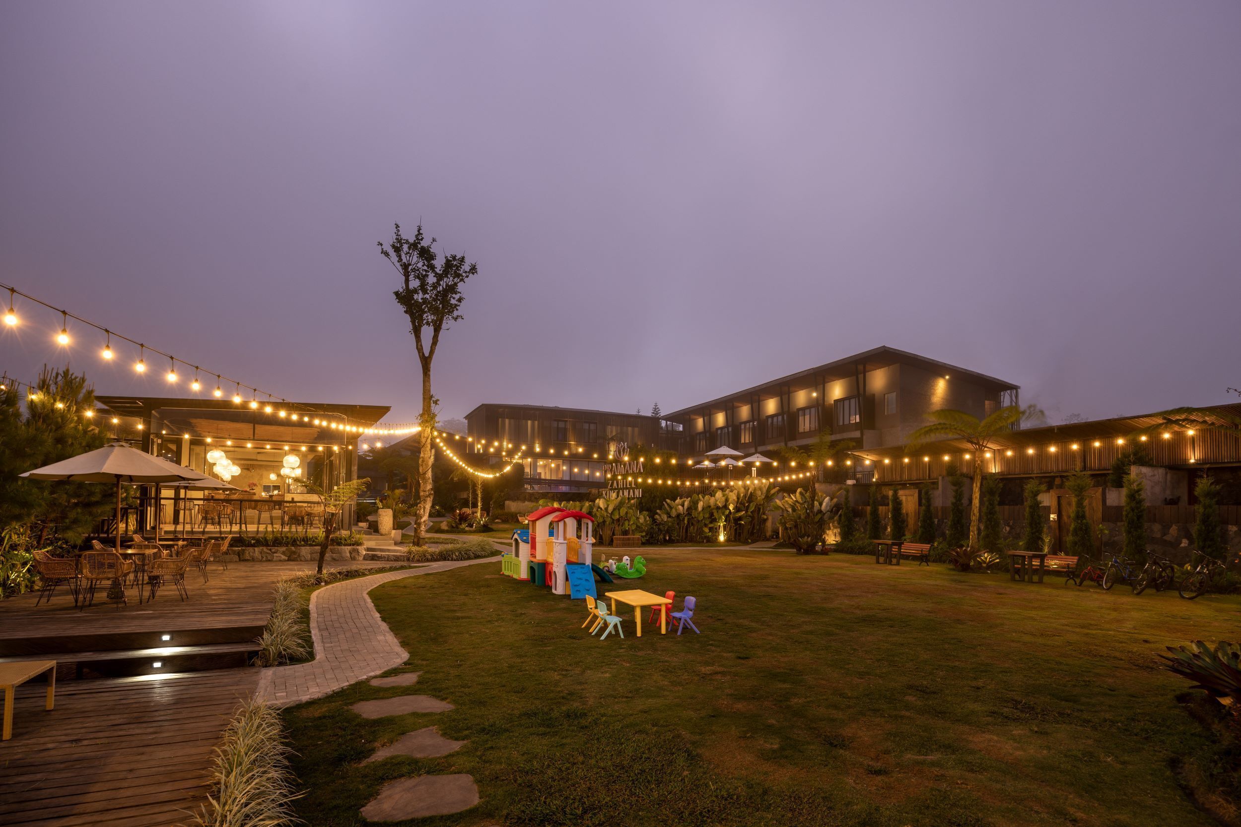 A courtyard with a play area, outdoor seating, and string lights.