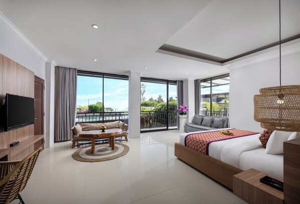 Een moderne hotelkamer met een groot balkon, een bank, een bed, een televisie en een eethoek.