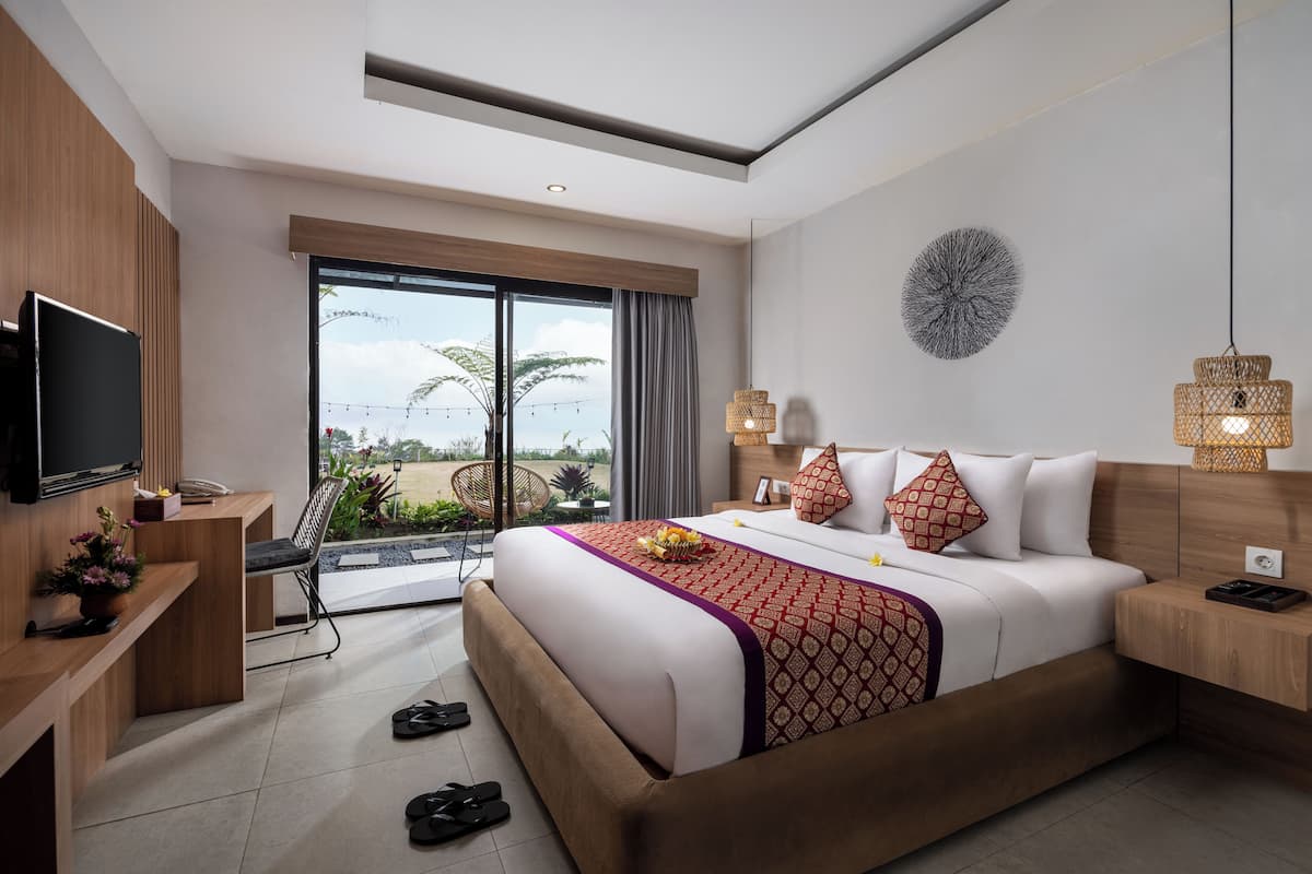 Een moderne hotelkamer met een groot bed, een televisie, een balkon met uitzicht en een eethoek.