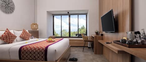 Habitación de hotel moderna con una cama grande, un escritorio, un televisor y vistas al exterior.