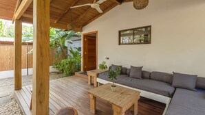 A wooden deck with a sofa and a table, a ceiling fan, and a hanging light fixture.