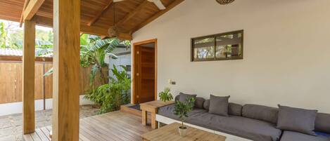 A wooden deck with a sofa and a table, a ceiling fan, and a hanging light fixture.