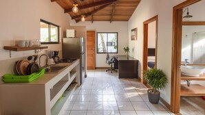 A compact kitchen with a refrigerator, sink, and a dining area with a chair and table.