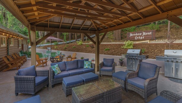 An outdoor patio area with wicker furniture, a barbecue grill, and a sign for Meadow Mont Lodge. - Arnold Meadowmont Lodge (Arnold)