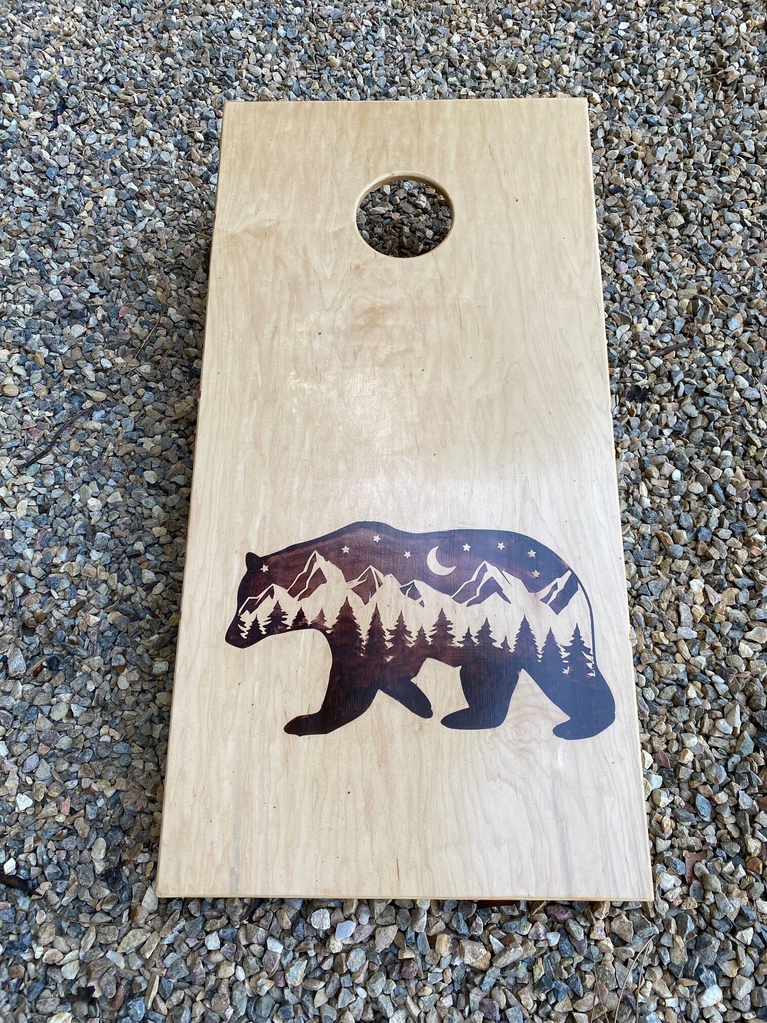 Een houten plank met een bergsilhouet en een cirkelvormig gat aan de bovenkant.