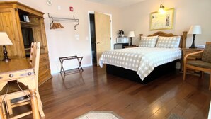 A bedroom with a bed, bedside tables, a desk, a chair, a ceiling fan, and a door leading to another room. - Arnold Meadowmont Lodge (Arnold)