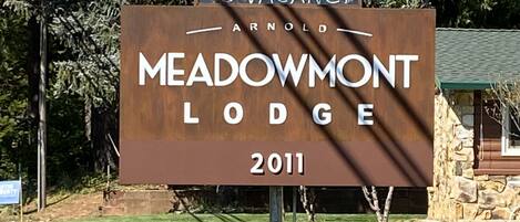A sign for Meadowmont Lodge with a lion sculpture.