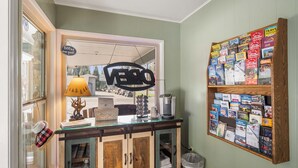 A reception desk with a mirror, a lamp, a coffee maker, and a bulletin board with travel brochures. - Arnold Meadowmont Lodge (Arnold)