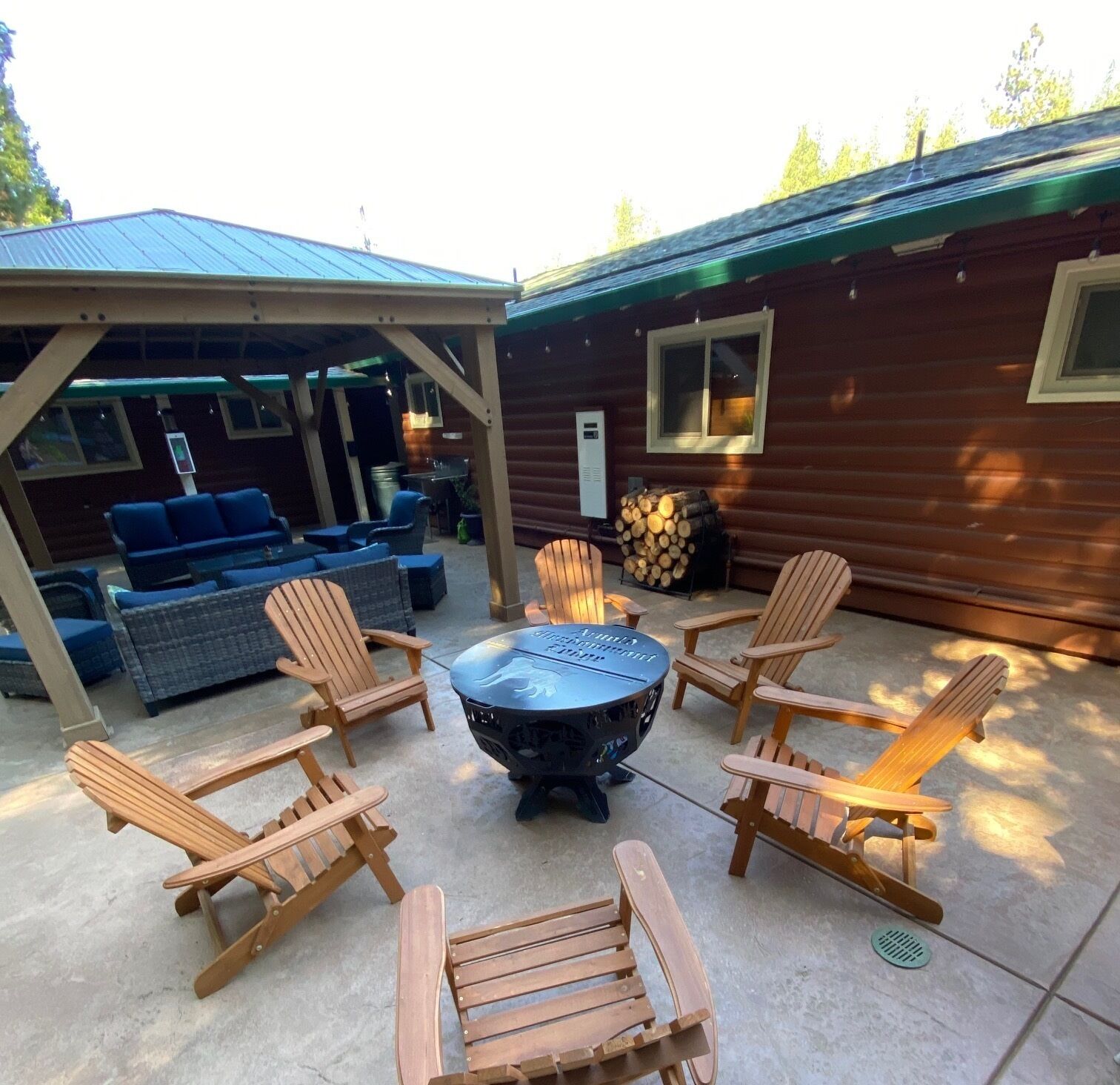 An outdoor patio with Adirondack chairs, a round table, and a covered seating area.