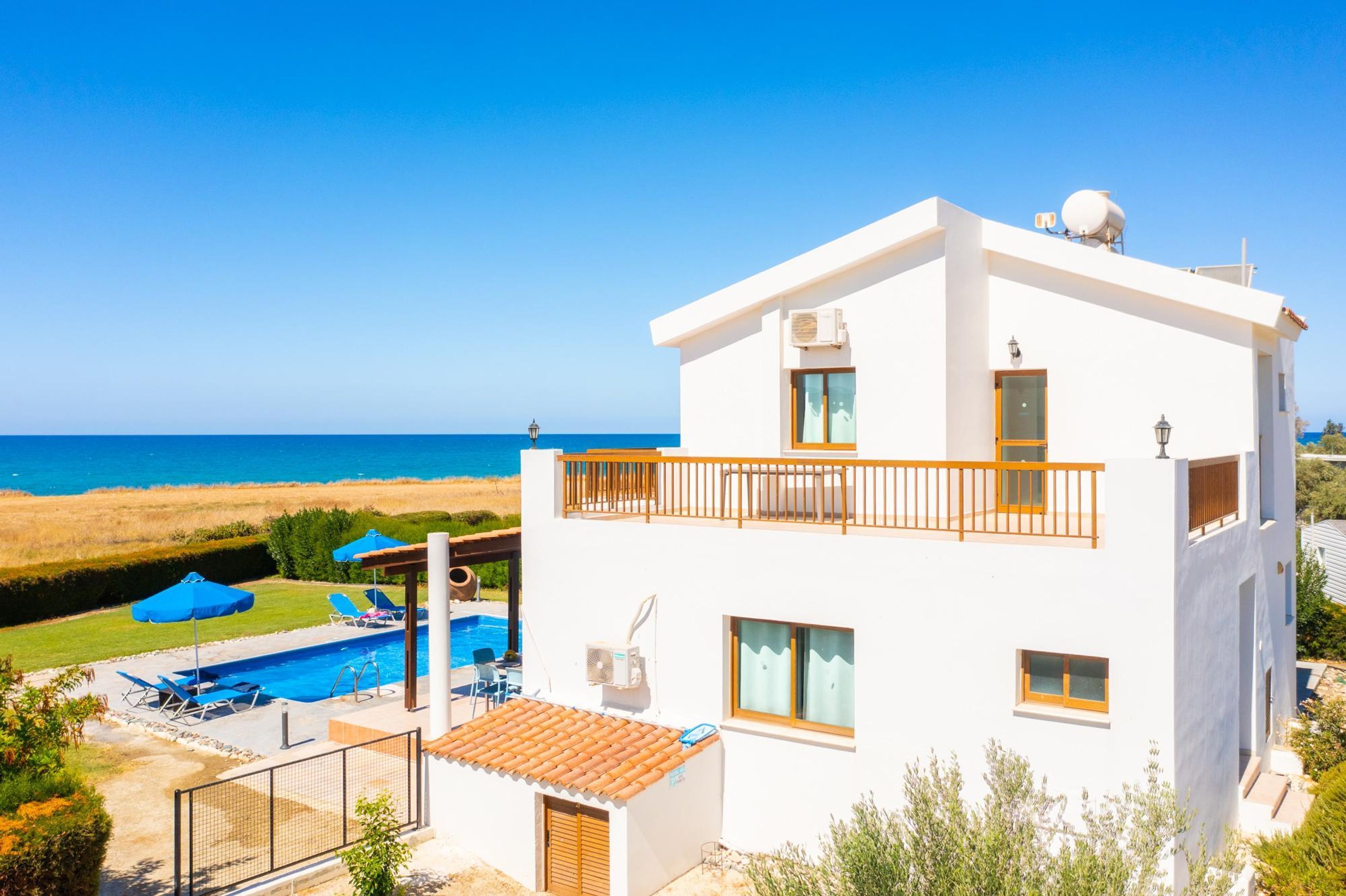 A modern two-story house with a balcony, a swimming pool, and a view of the sea.