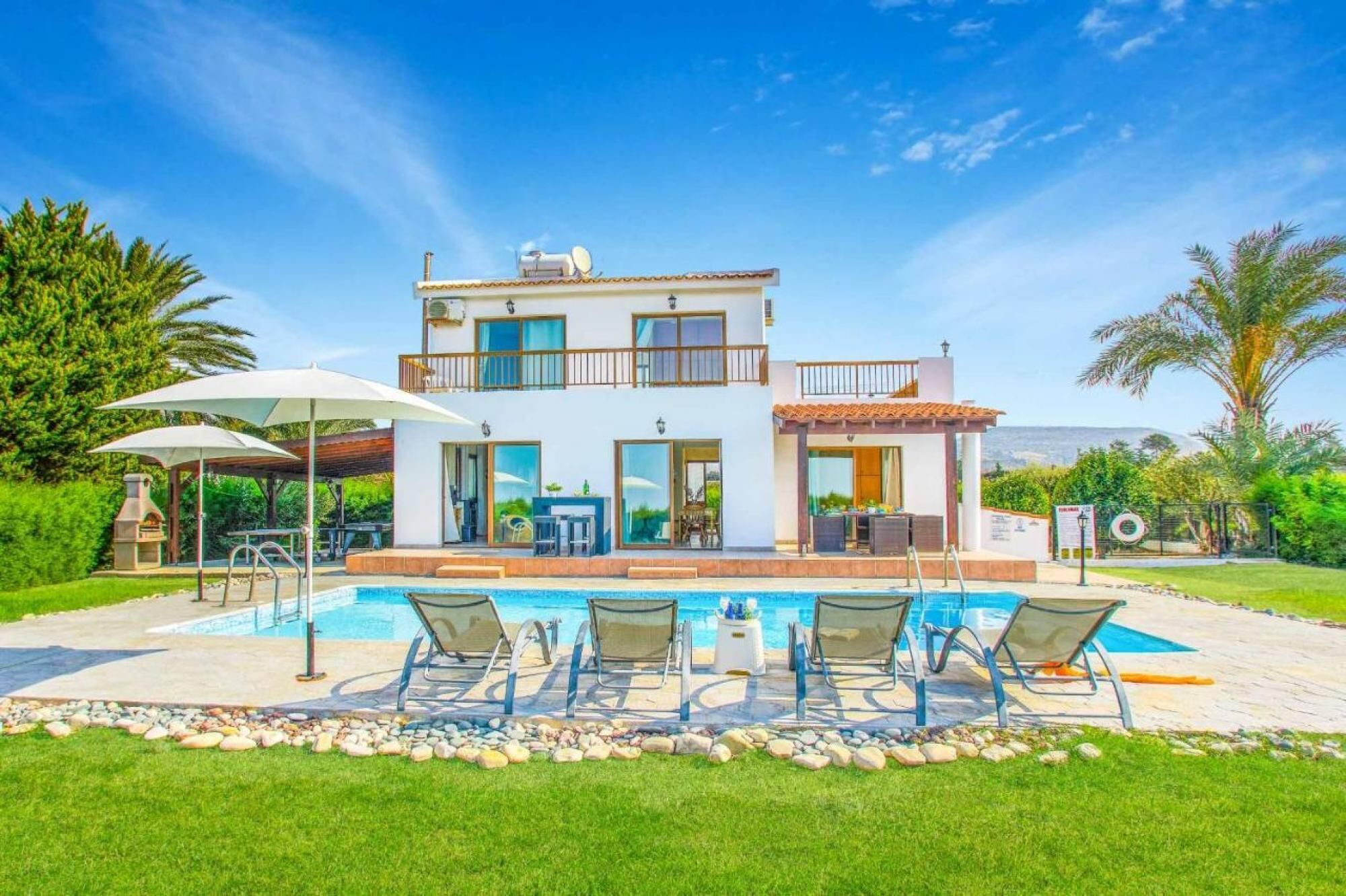A two-story house with a swimming pool, outdoor seating, and a barbecue area.