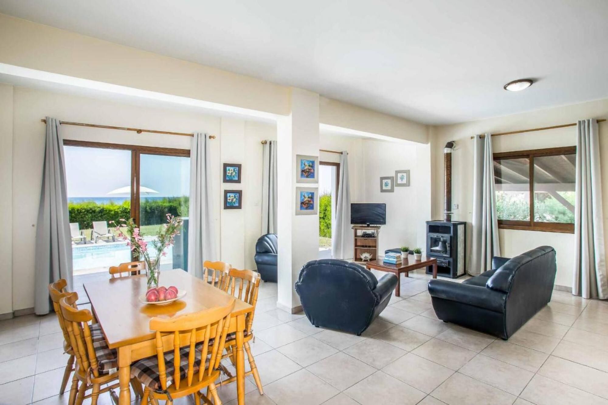 A spacious living area with a dining table, chairs, a sofa, and a television.
