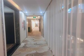 A hotel corridor with a patterned carpet, a door on the left, and a curtain on the right. - Nangang City Hotel (Shenzhen)