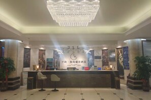 A hotel reception area with a chandelier, reception desk, and potted plants. - Nangang City Hotel (Shenzhen)