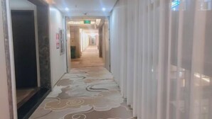 A hotel corridor with patterned carpet, white curtains, and a ceiling with recessed lighting. - Nangang City Hotel (Shenzhen)