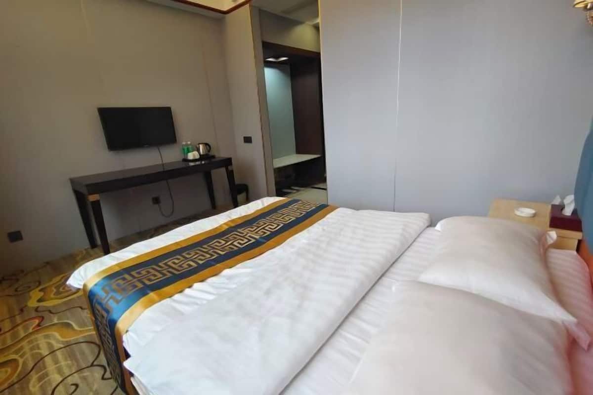 Une chambre d’hôtel équipée d’un lit, d’un bureau, d’une télévision et d’une armoire.