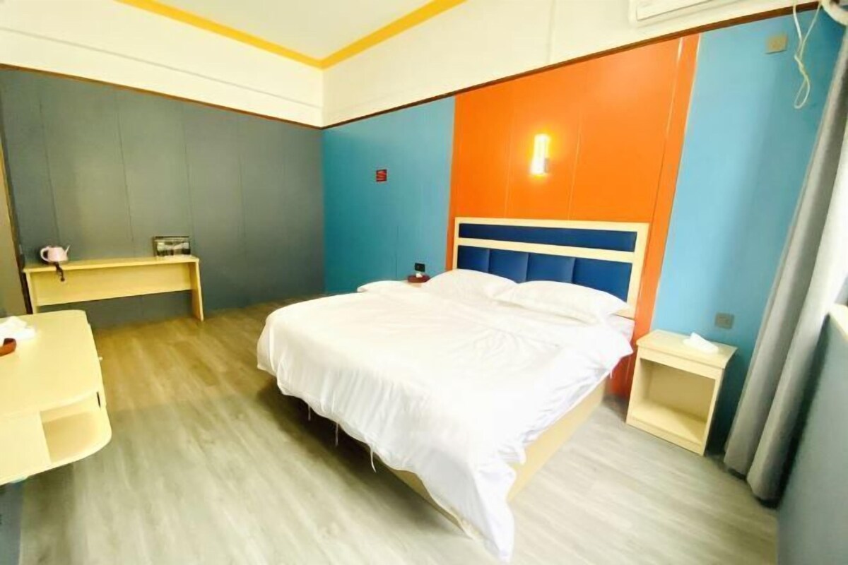 A hotel room with a bed, bedside tables, a desk, and a chair.