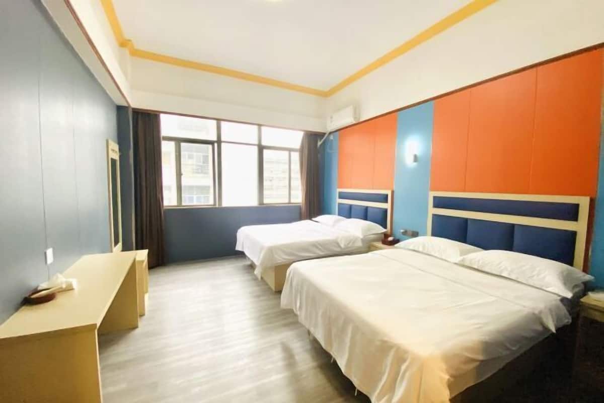 Une chambre d’hôtel avec deux lits, un bureau et une fenêtre.