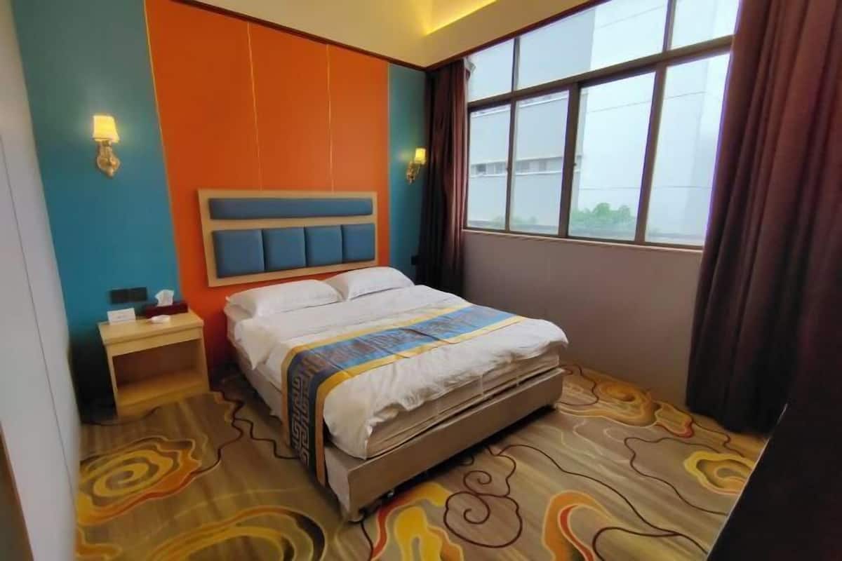 Une chambre d’hôtel avec un lit, une table de chevet et une fenêtre avec des rideaux.