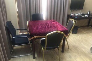 A room with a table covered by a red cloth, four chairs, a desk with a computer, and a TV. - Nangang City Hotel (Shenzhen)