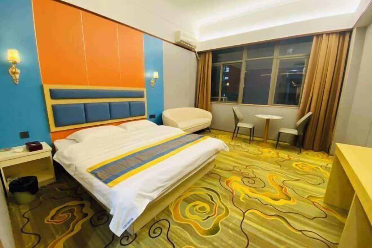 Une chambre d’hôtel avec un lit, une table de chevet, une lampe et une petite table avec des chaises.