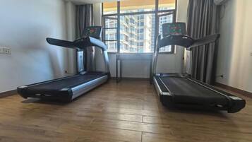A room with two treadmills, a window with a view of buildings, and a wooden floor.