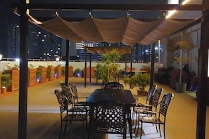 An outdoor dining area with a table and chairs, surrounded by potted plants and a canopy. - Holiday inn Aegean Port (Huidong)
