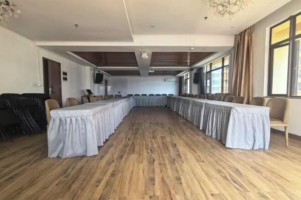 Una sala de conferències amb una taula llarga, cadires i un paviment de fusta.