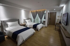 Two single beds with white bedding and dark blue accents, accompanied by bedside tables and lamps, offer a comfortable retreat.