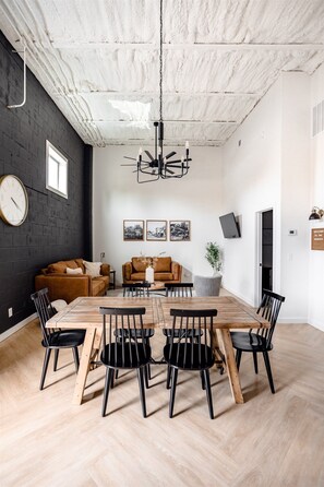 A modern living room with a wooden dining table, black chairs, a brown sofa, and a hanging light fixture. - High-end luxurious loft within walking distance to downtown! (Mountain Home)