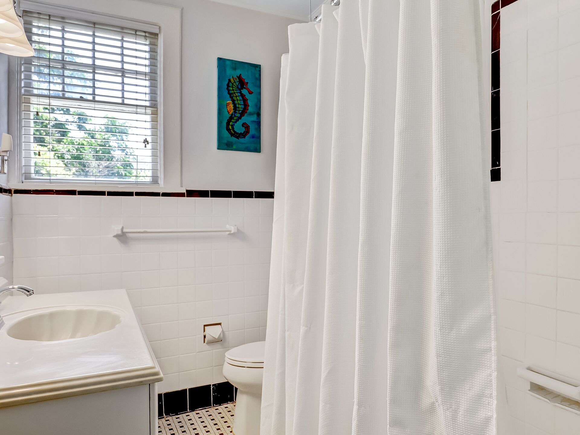 Une salle de bain avec un lavabo blanc, des toilettes et un rideau de douche.