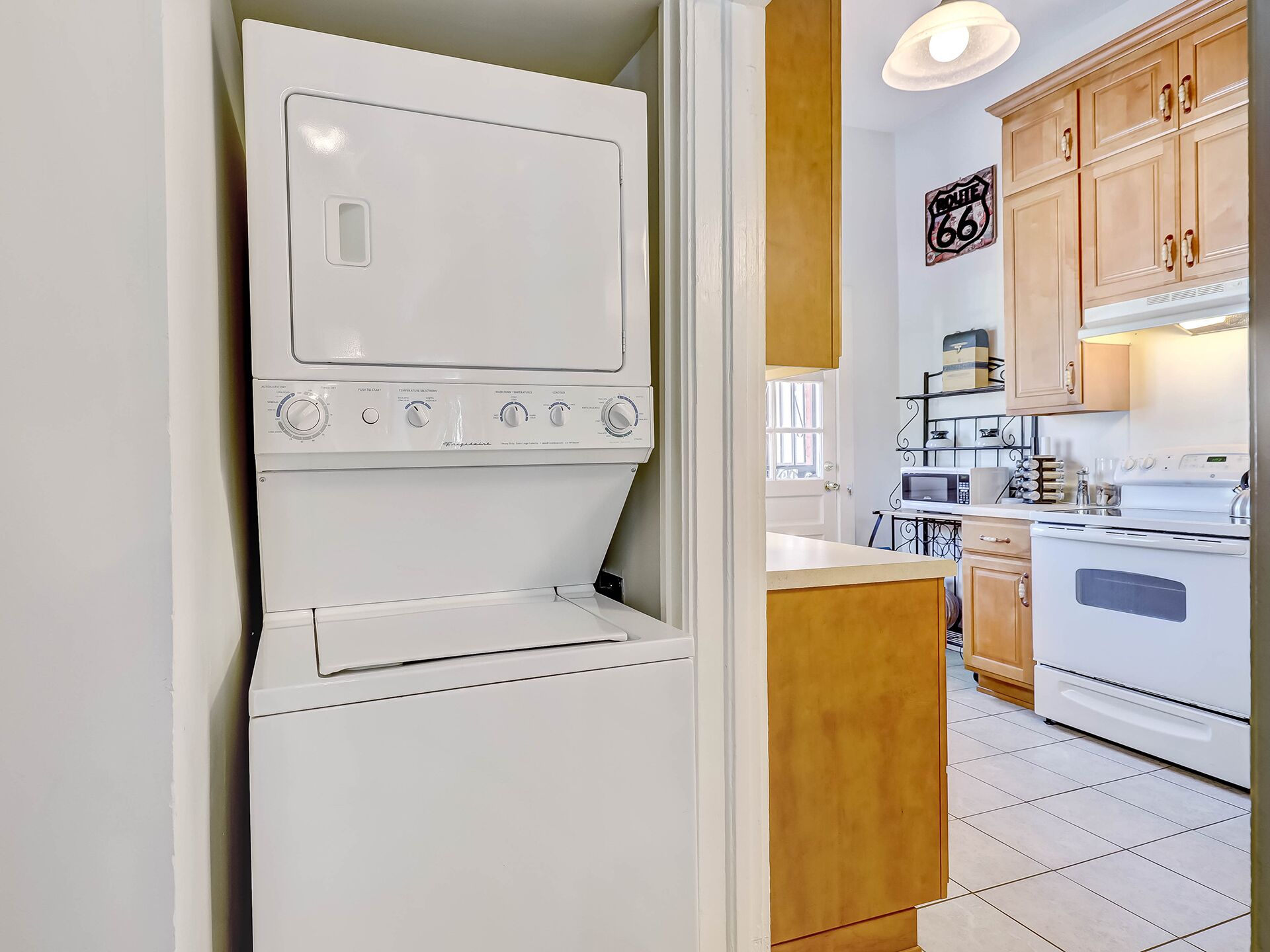 A compact kitchen with a built-in washer and dryer, wooden cabinets, and a tiled floor.