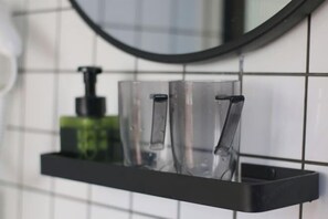 A bathroom with a black shelf holding clear glasses and a green bottle. - Qianzihu Boutique Guesthouse (Fuzhou)